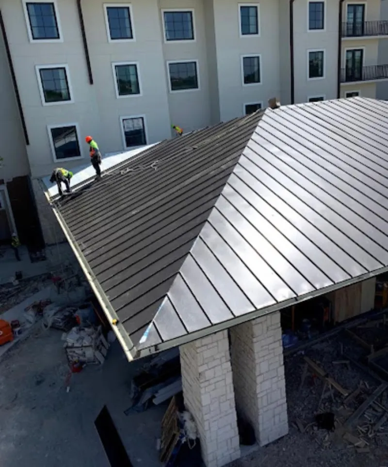Crew installing standing seam metal roof panels on a commercial project in Maywood